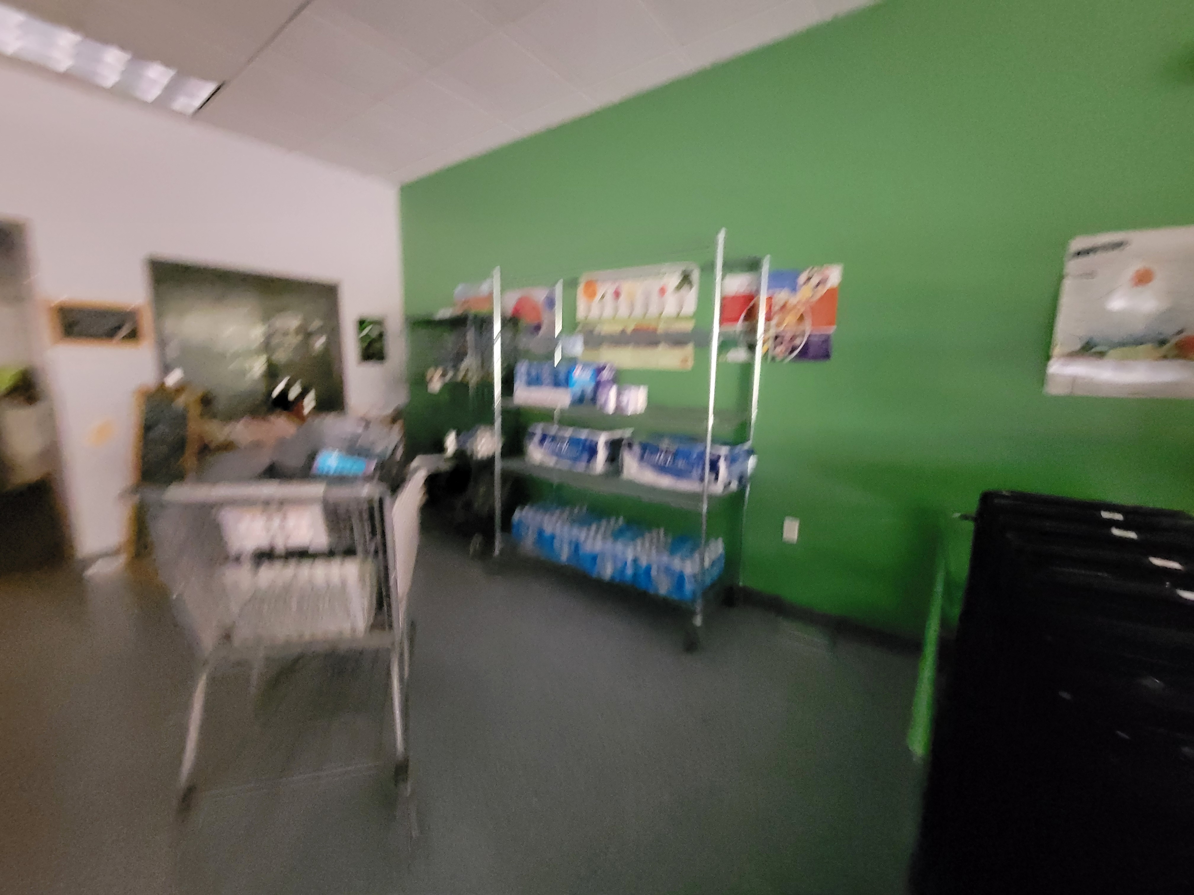 Shopping area with items filled shelves plus office to the left, a shopping cart in the middle and rows of shopping carts to the right.